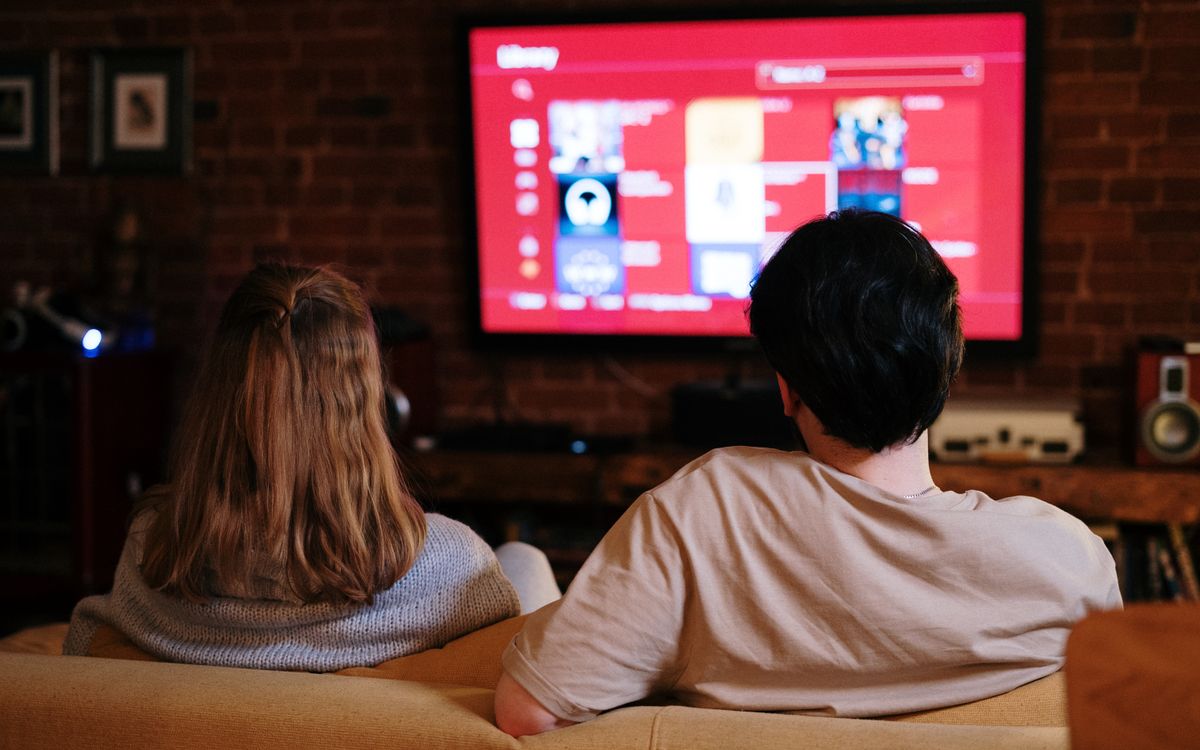 A couple watching television together in a brick-walled living room