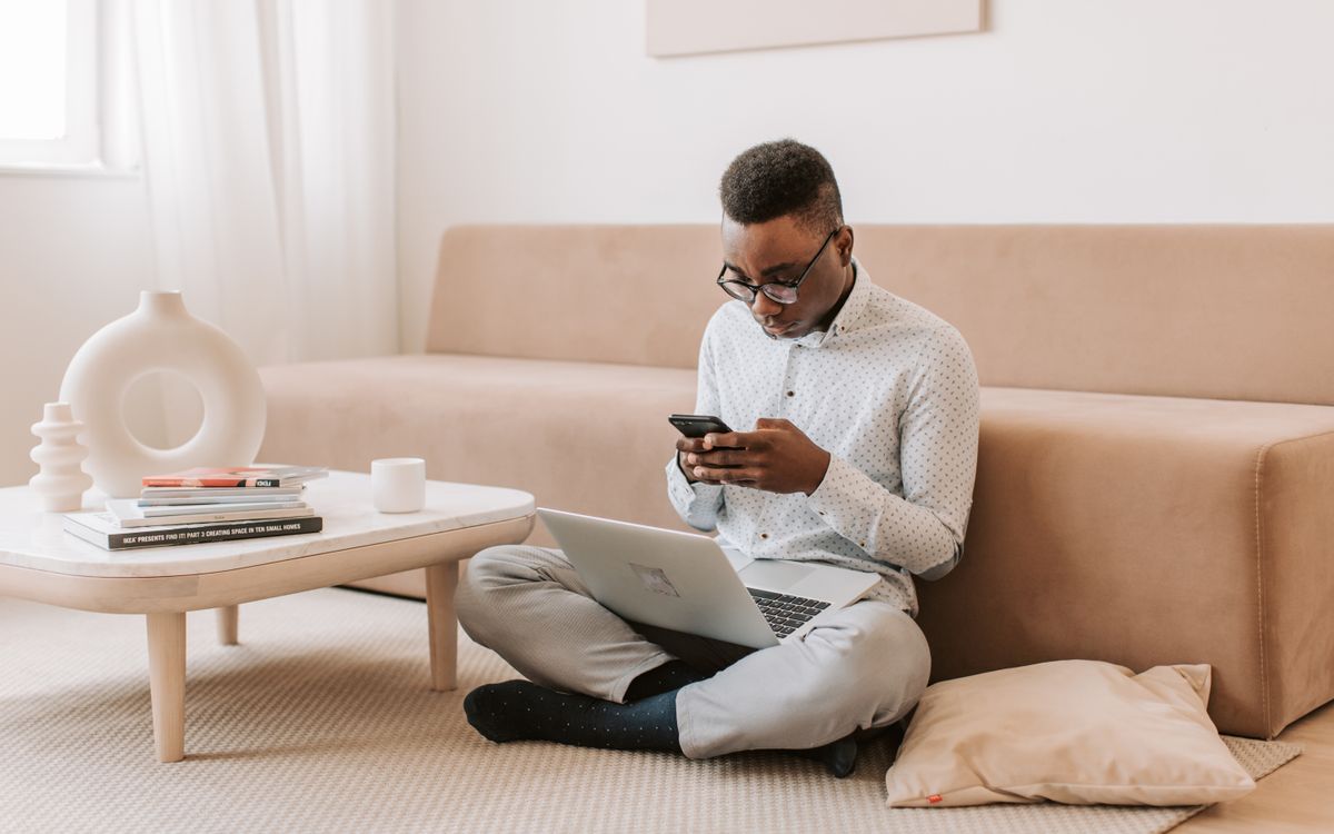 A person using a smartphone and laptop in a living room